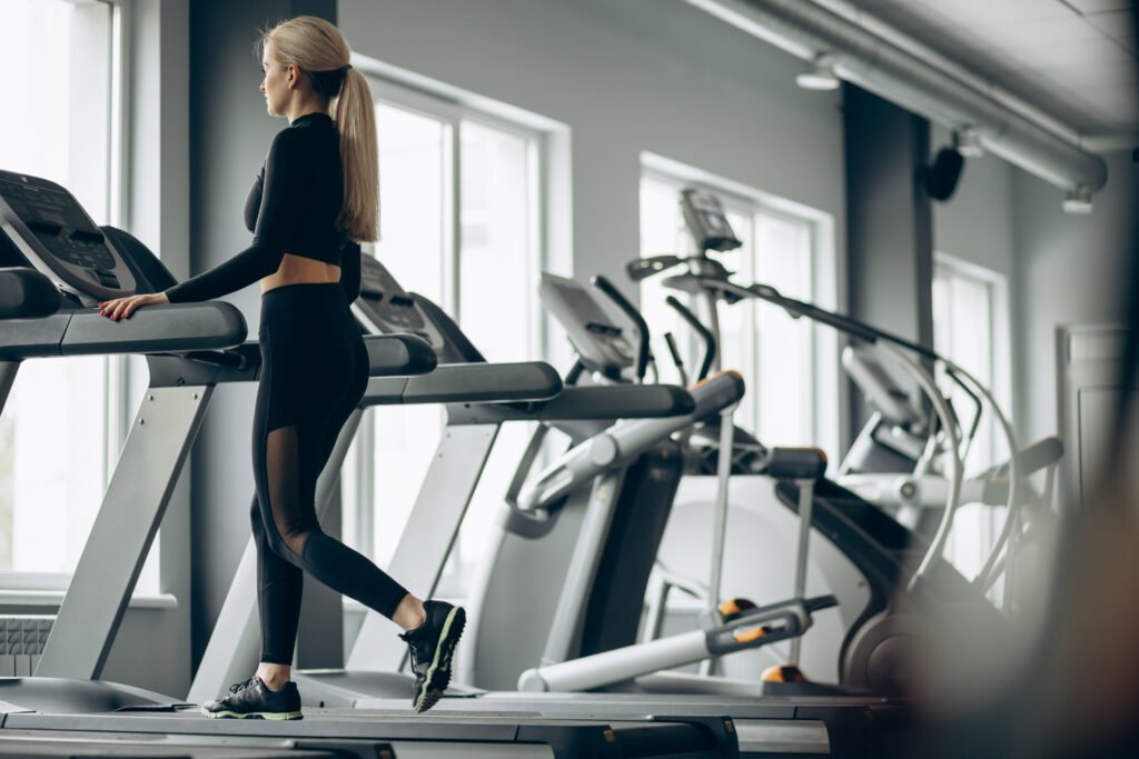 Sporty woman running on treadmill at the gym